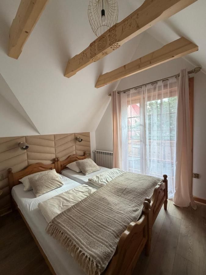 Sypialnia pod skosem z dwoma łóżkami i belkami z rzeźbionym ornamentem