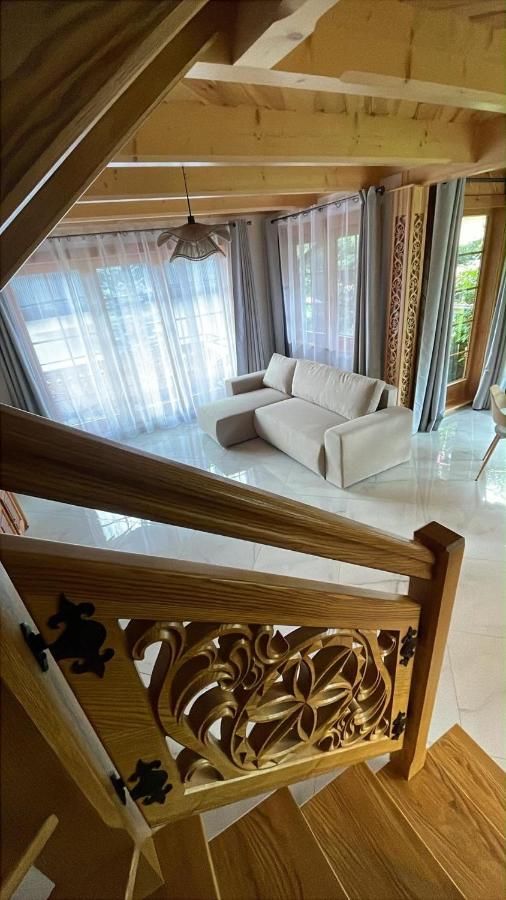 Rzeźbiona balustrada schodów, w dole jasny salon