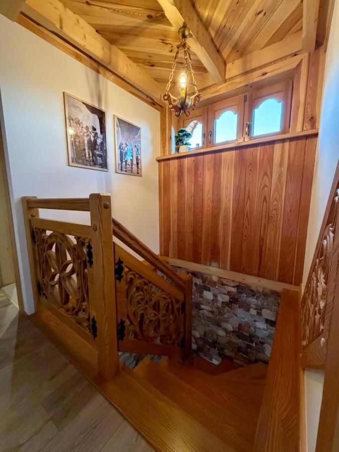Drewniane schody z rzeźbioną balustradą i lampą pod drewnianym sufitem
