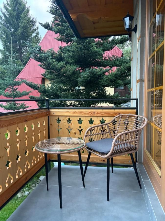 Balkon z ażurową drewnianą balustradą, stolikiem i fotelem