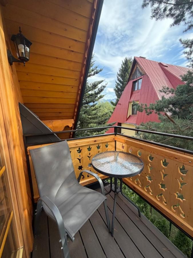 Balkon z ażurową balustradą, stolikiem i krzesłem